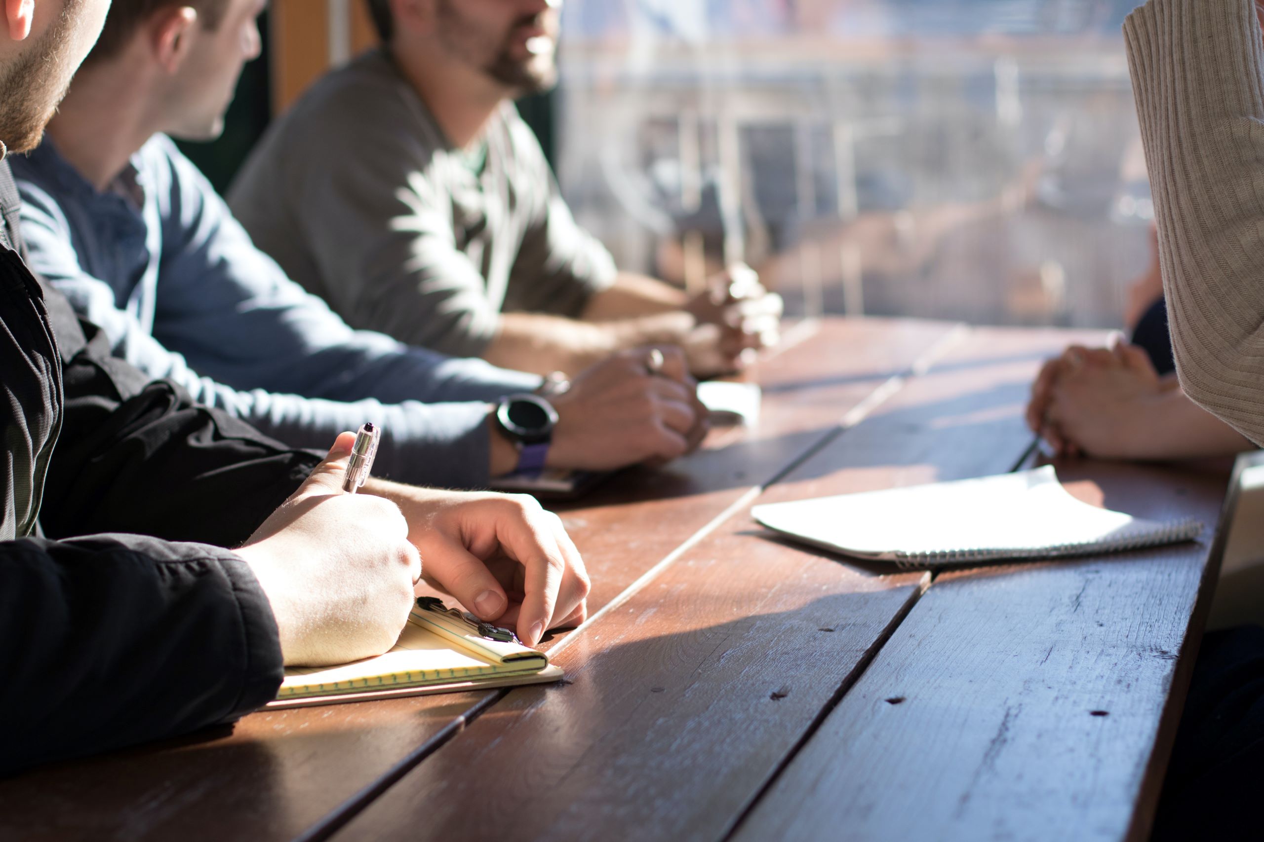 A diverse group of professionals sitting at a conference table, collaborating and brainstorming ideas with a pen in hand.