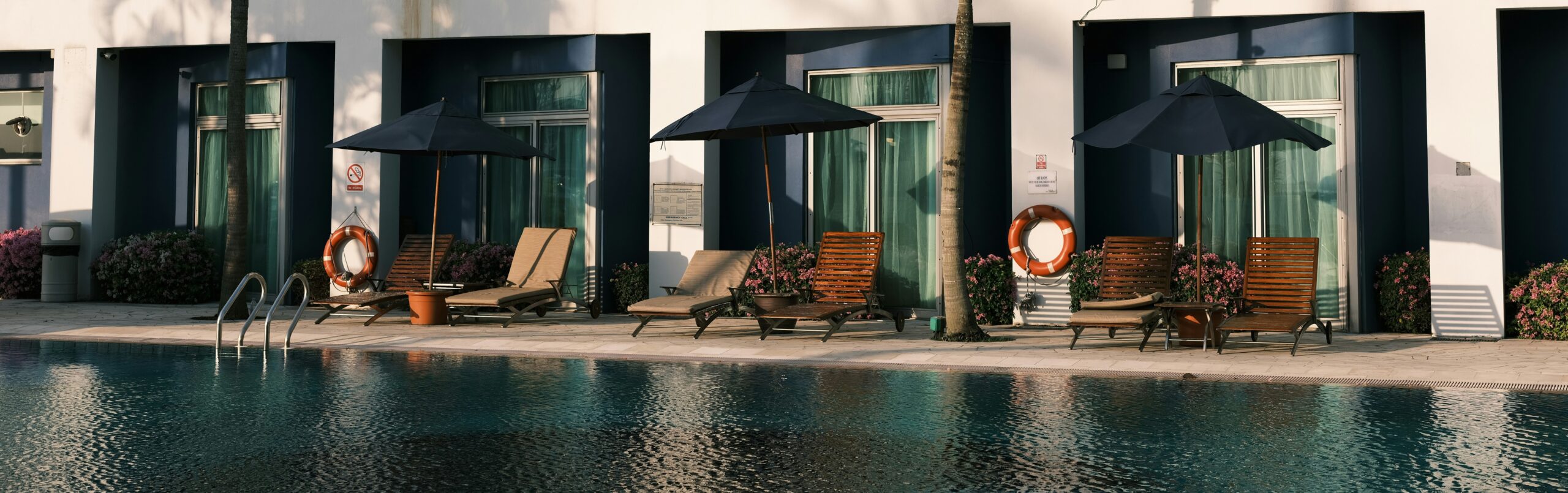 A row of chairs and umbrellas by a pool on a sunny day