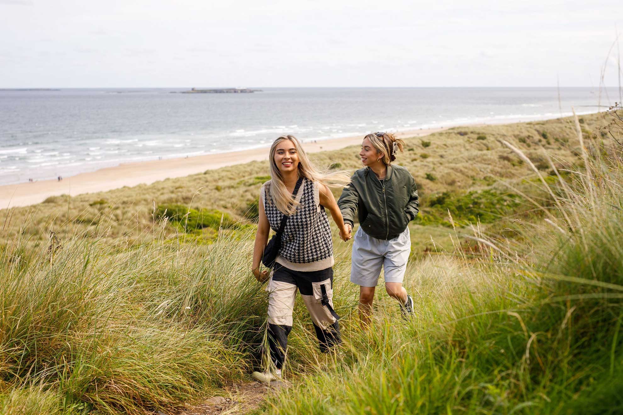 Two young woman walking by a beach