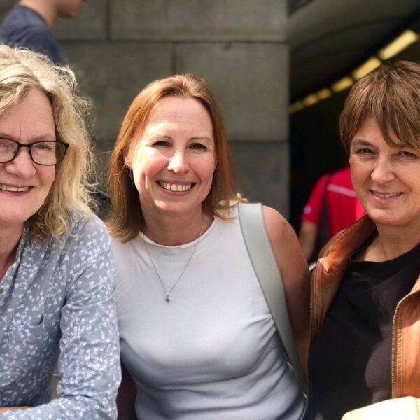 Three women posing for a picture, smiling happily.